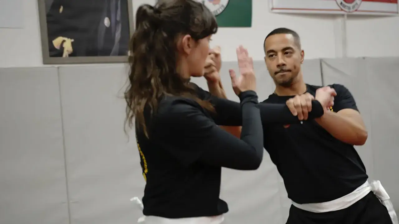 Man och kvinna tr&auml;nar wing chun i en dojo. De &ouml;var p&aring; blockeringar och slag.