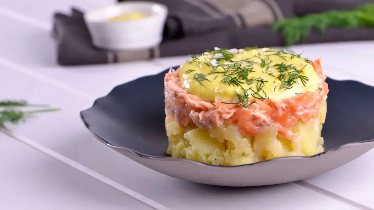 Delicioso timbal de patata con salmón ahumado y mayonesa, decorado con eneldo fresco y sal gruesa.