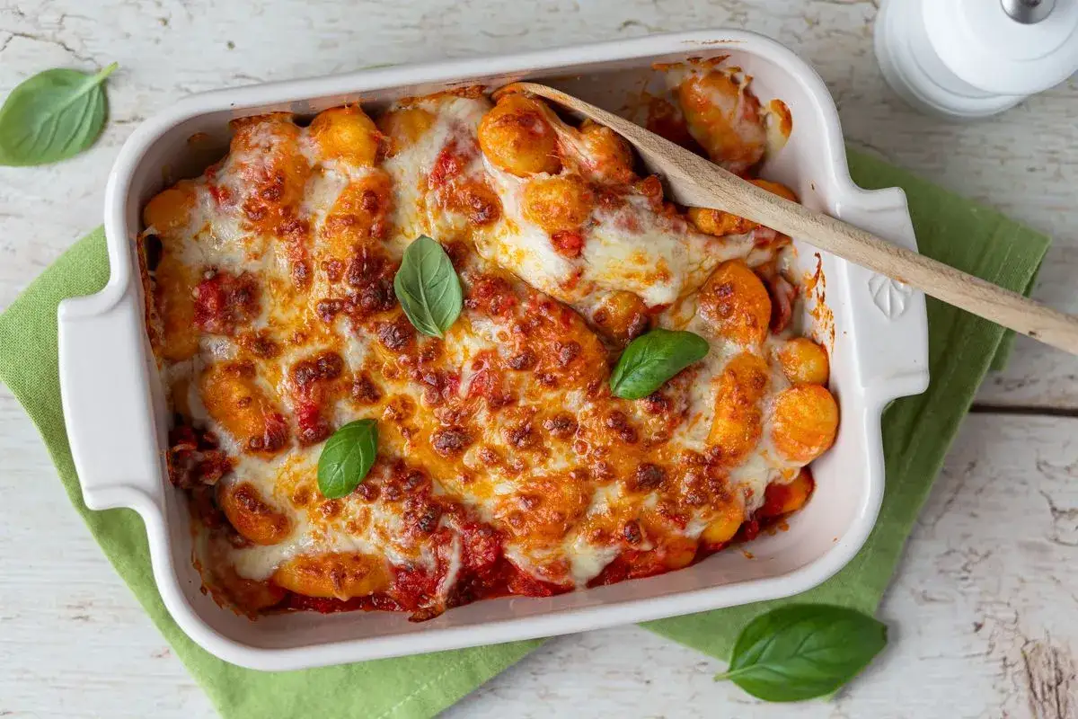 Gnocchi au chorizo gratinés, sauce tomate et fromage fondant, décorés de feuilles de basilic frais. Un plat réconfortant prêt à être dégusté.