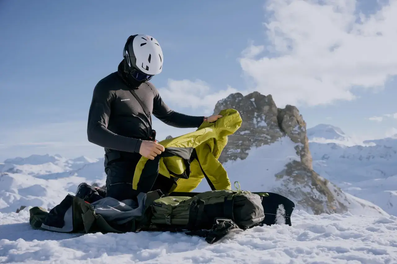 Esquiador se prepara en la montaña, decidiendo entre abrigo Primaloft vs Gore-Tex para el clima.