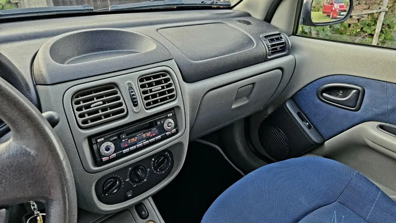Wnętrze Renault Thalia 1.4 z niebieskimi akcentami na siedzeniu i drzwiach. Widoczny panel radia i nawiewy.