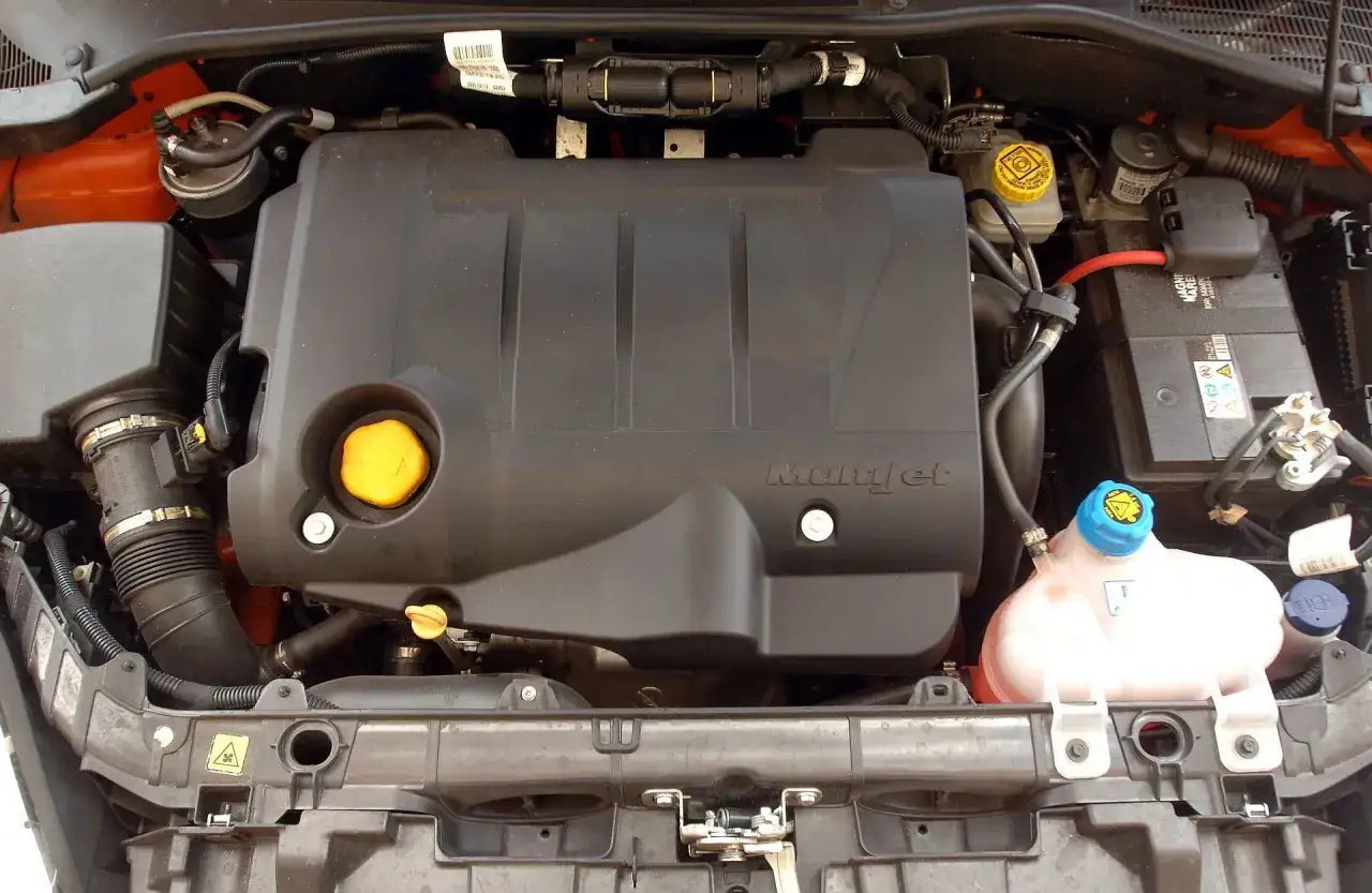 Silnik MultiJet w Fiat Grande Punto 1.4. Widoczny jest czarny plastikowy wlot powietrza, zbiornik płynu chłodniczego i akumulator.