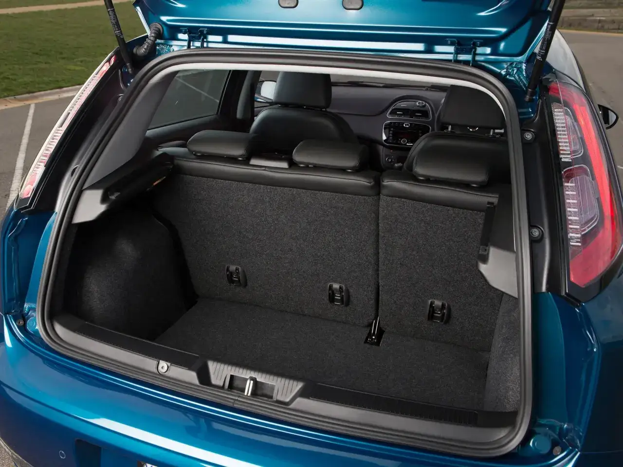 Błękitny Fiat Grande Punto 1.4 z otwartym bagażnikiem. Wnętrze czyste, siedzenia z tyłu złożone, gotowe na bagaże.