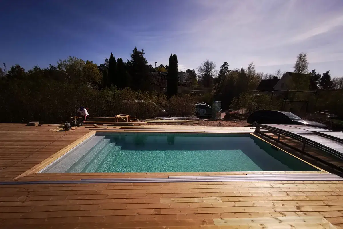 Bygga in pool i tr&auml;dg&aring;rden. En person arbetar med trall runt den nya poolen.