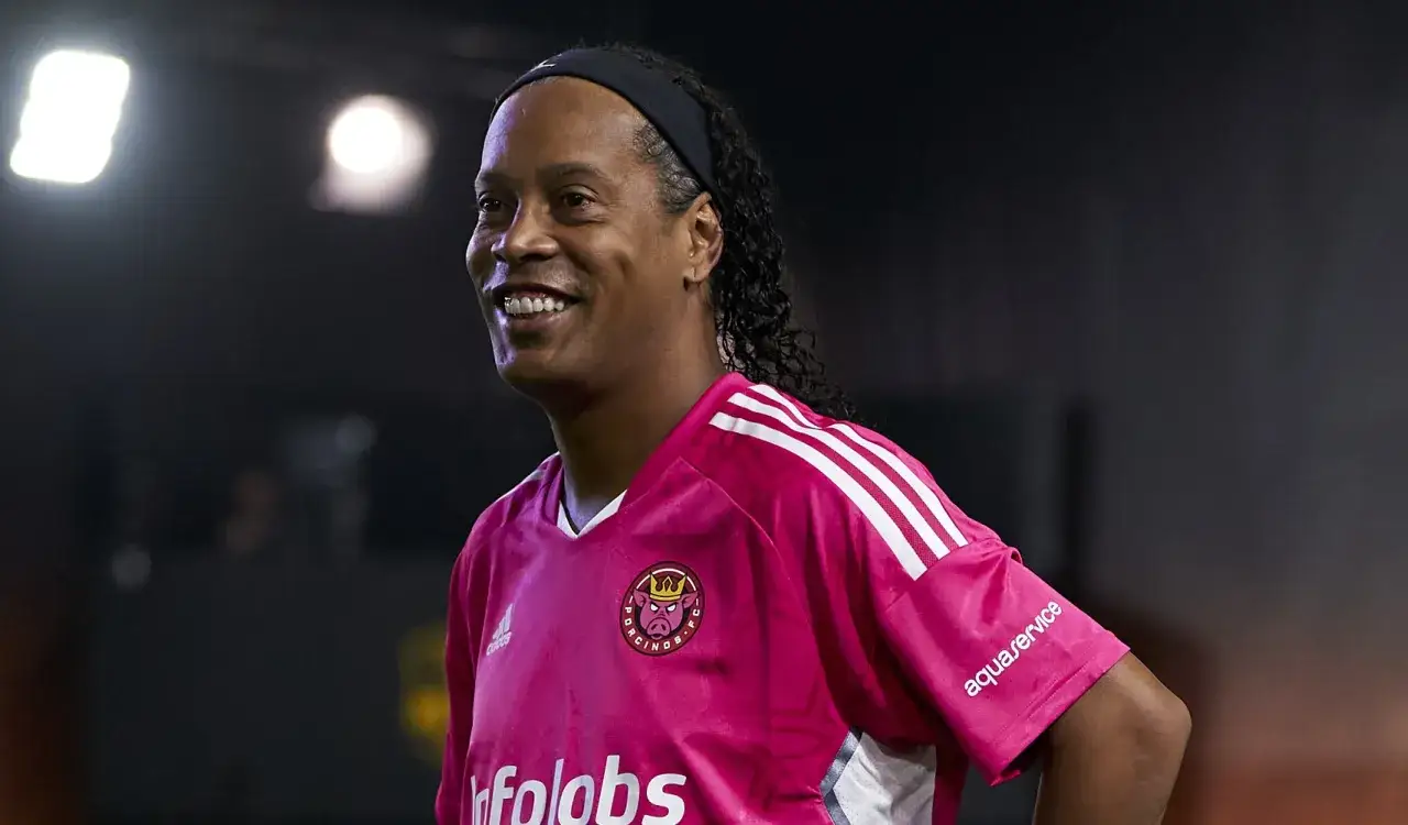 Uśmiechnięty Ronaldinho w różowej koszulce z logo 