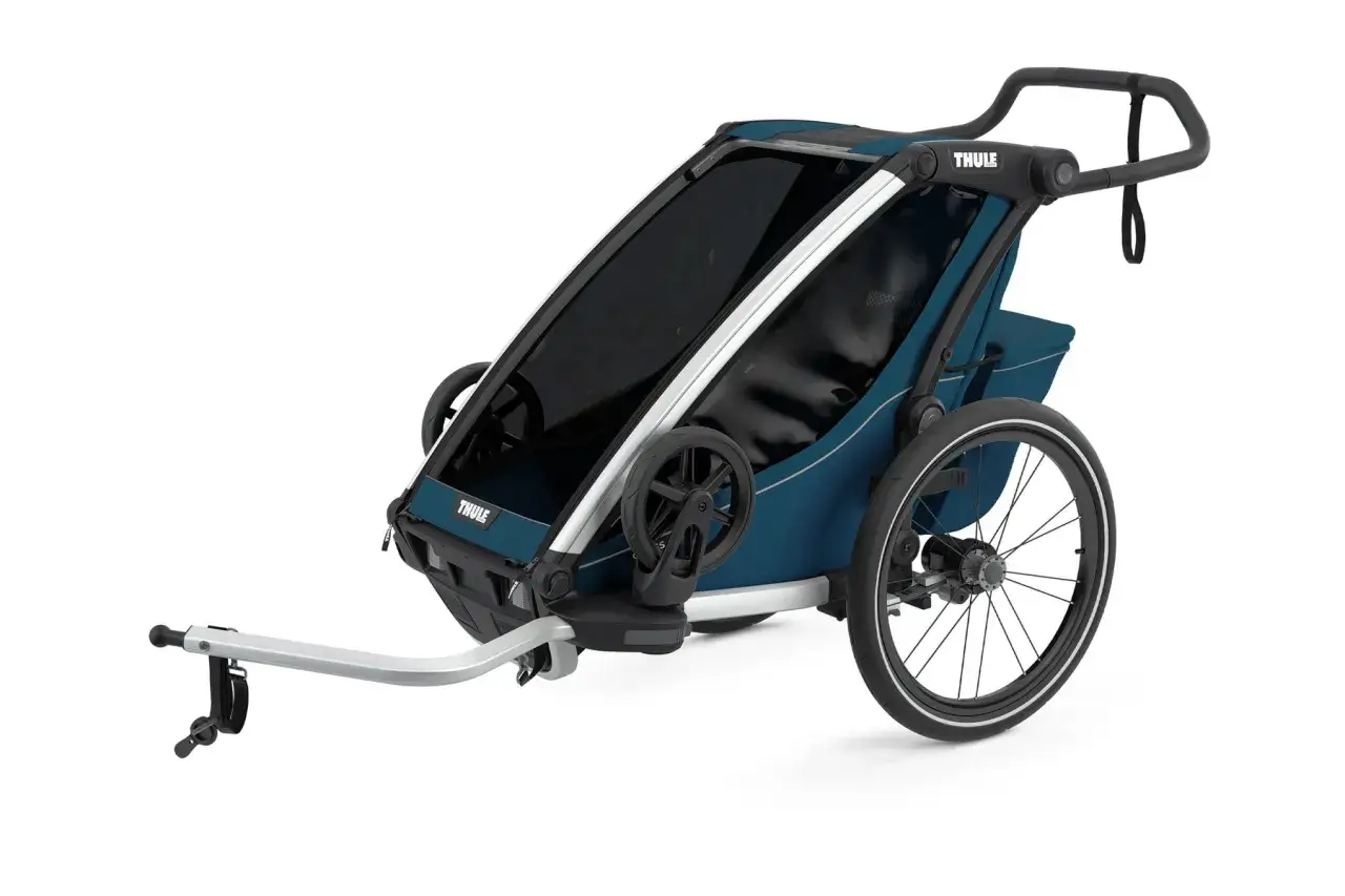 En bl&aring; Thule cykelvagn med stora hjul och dragst&aring;ng. Perfekt f&ouml;r &auml;ventyr med barnen.
