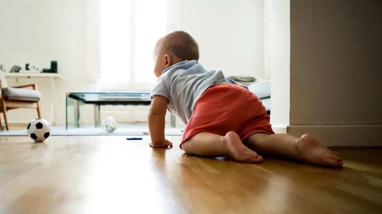 Bambino gattona verso un pallone da calcio, esplorando il mondo. A quanti mesi si gattona? Forse a questo piccolo esploratore.