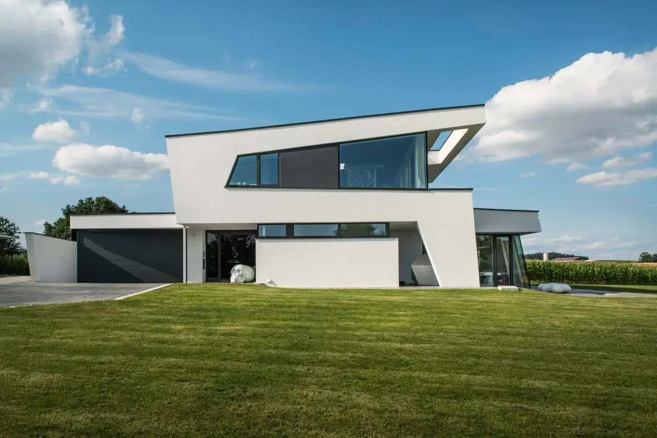 Modernes Haus mit Garage und Rasen. Das schräge Dach, ein Pultdach, ist ein markantes architektonisches Merkmal.