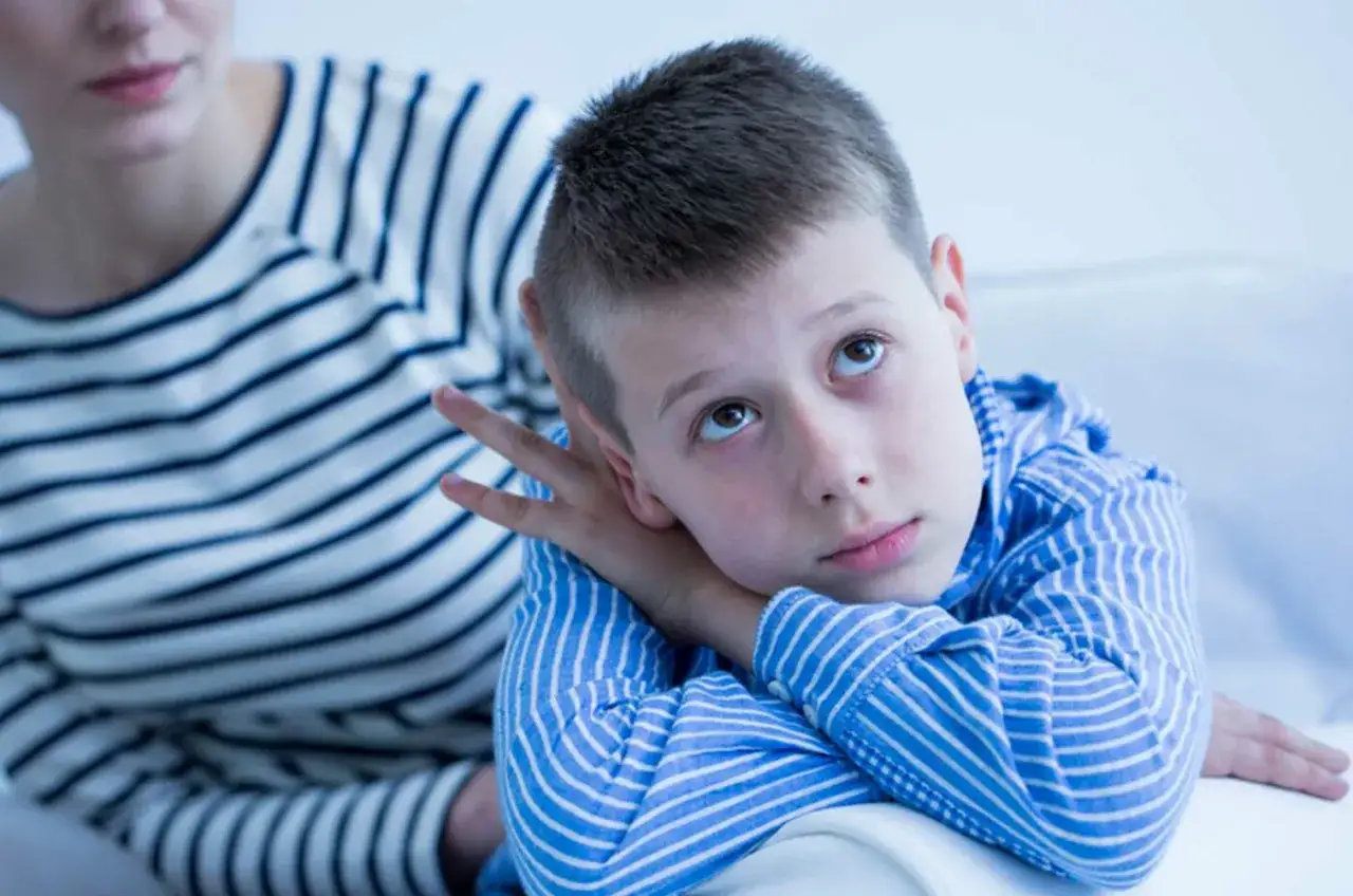 Un bambino con sguardo pensieroso, un possibile segnale per come riconoscere un bambino autistico. La madre lo osserva con attenzione.