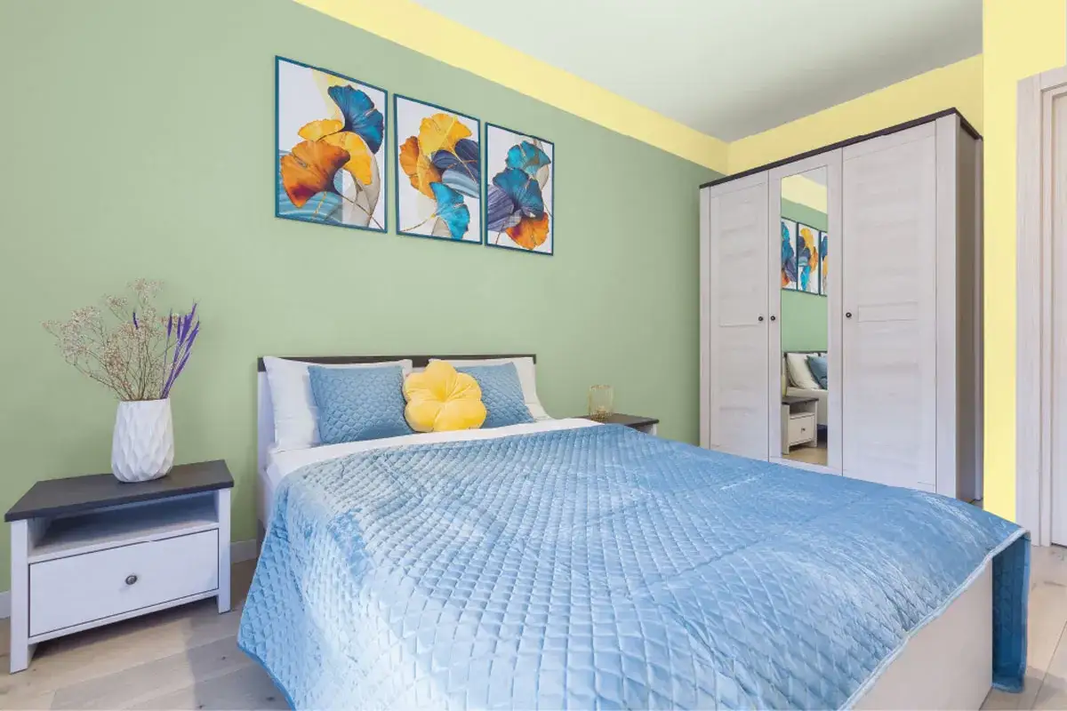 Dormitorio con paredes verde menta y detalles amarillos en el techo. Cama azul, mesita de noche y armario blanco. Ideas de colores para pintar un dormitorio peque&ntilde;o.