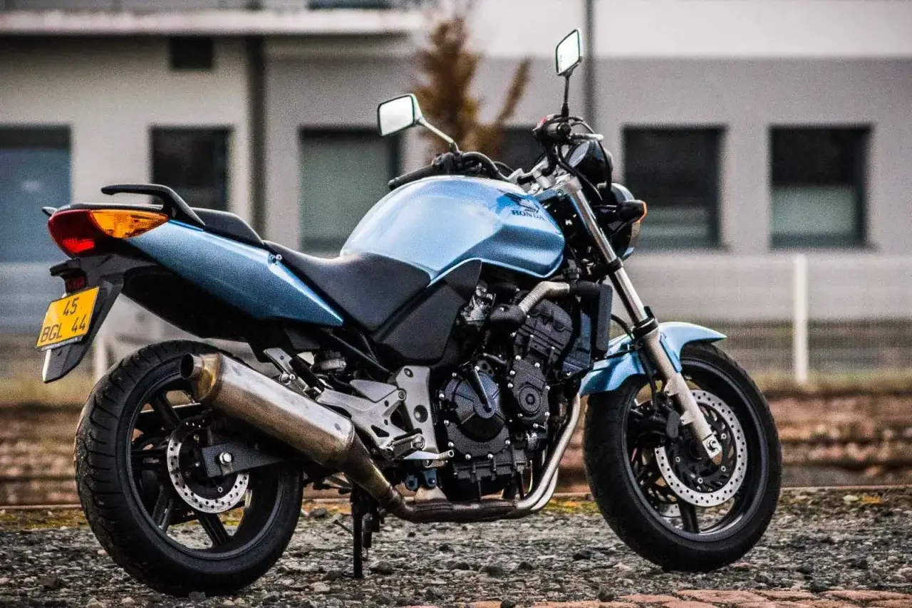 Błękitny motocykl Honda CBF 600, z widoczną wysokością siedzenia, stoi na żwirze.