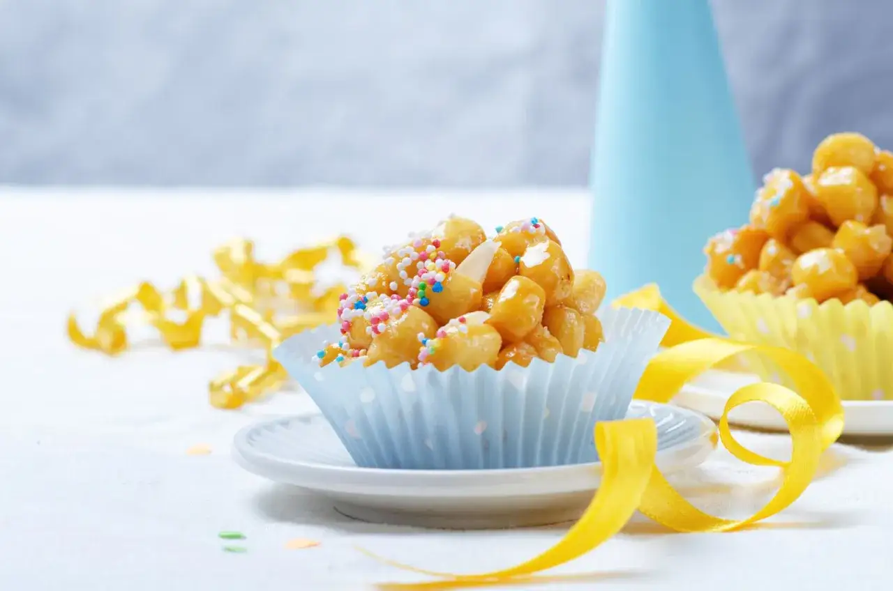 Dolci di carnevale marchigiani, palline dorate ricoperte di zuccherini colorati, pronte per una festa.