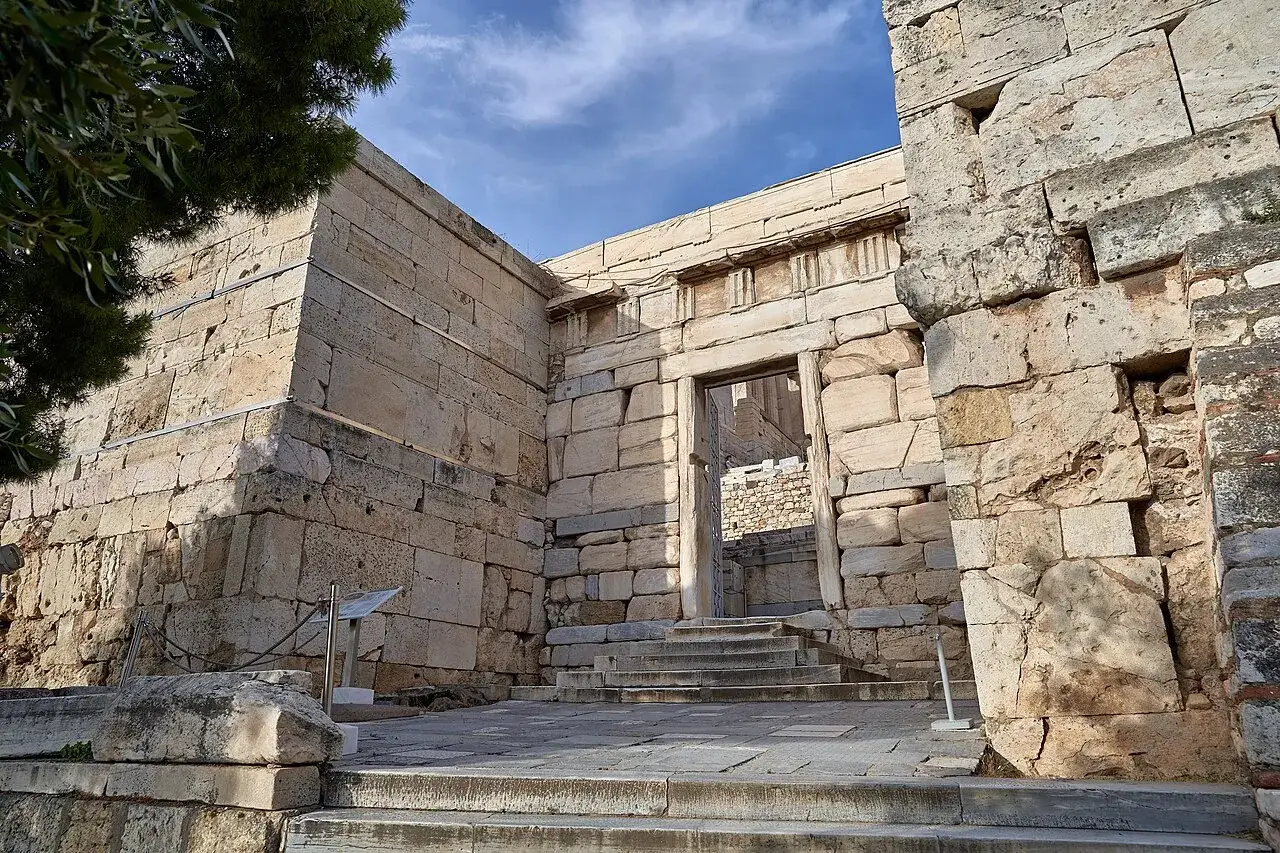 Ancient stone steps lead through a grand doorway, hinting at how hard is the walk up to the Acropolis.