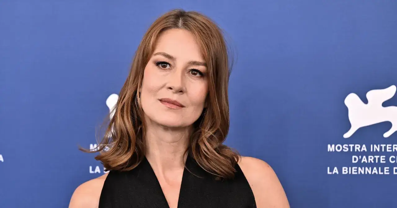 Maja Ostaszewska, znana z wielu filmów, na tle niebieskiej ścianki z logo festiwalu filmowego.