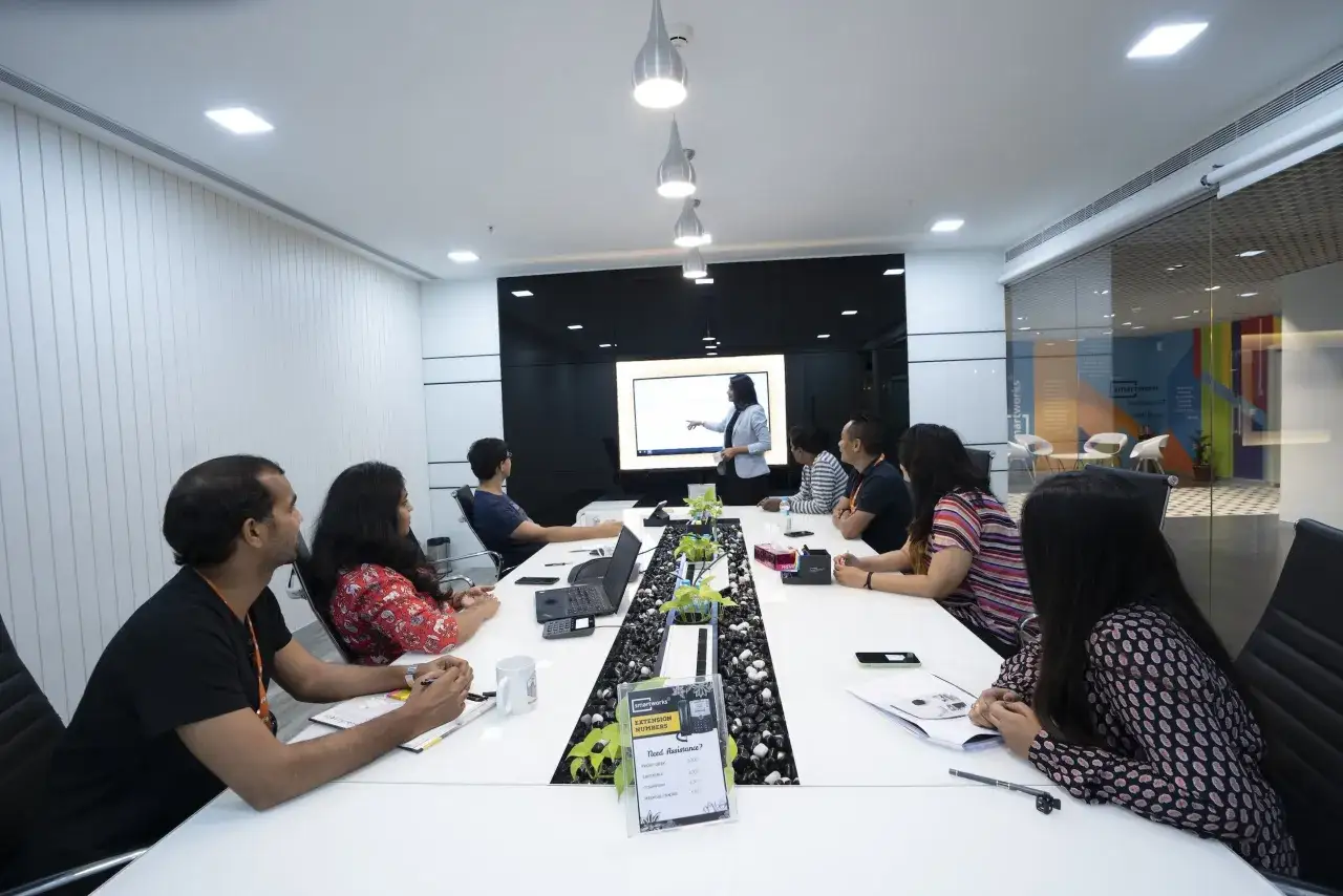 A team participates in an executive leadership development training session, with a presenter at a large screen.