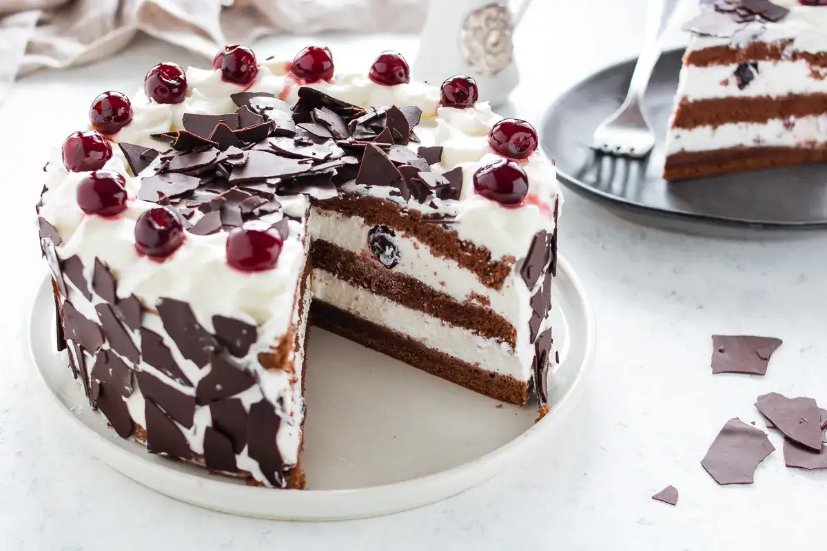 Una fetta di foresta nera dolce, con strati di cioccolato, panna e ciliegie, decorata con riccioli di cioccolato e ciliegie fresche.