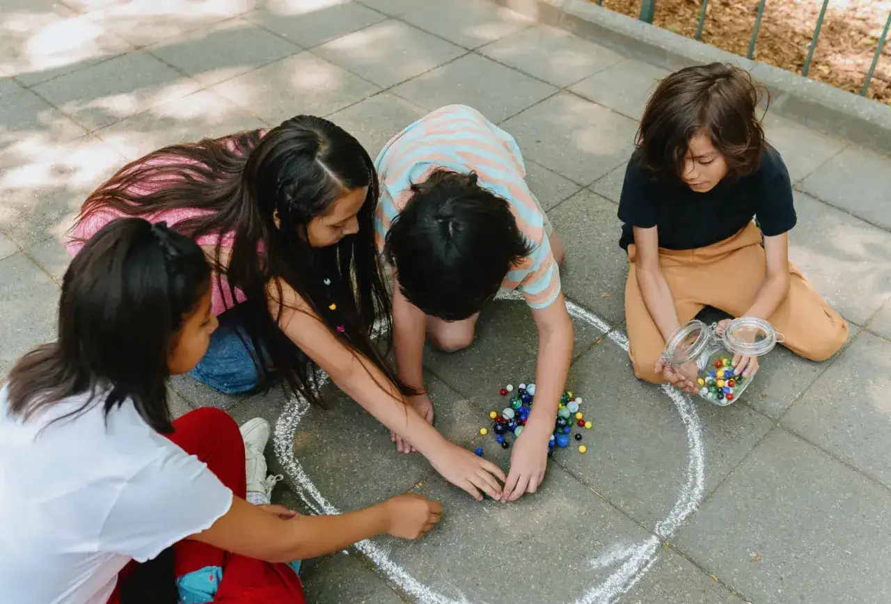 Ni&ntilde;os jugando a las canicas, reviviendo los juegos de antes en la calle.