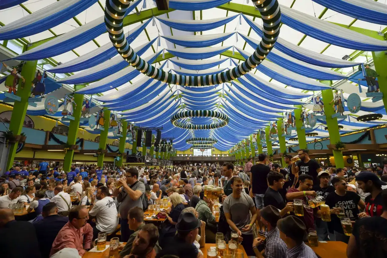 Un tendone decorato con bandiere blu e bianche, pieno di gente che festeggia e beve birra. &Egrave; l'atmosfera tipica di dove si svolge l'Oktoberfest.