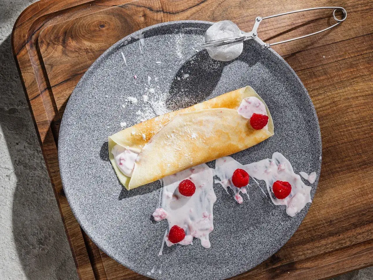 Ein leckerer Crêpe, gefüllt mit einer cremigen Masse und frischen Himbeeren, bestäubt mit Puderzucker. Perfekt für ein schnelles Crêpes Rezept.