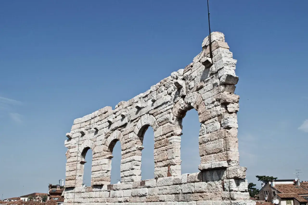 L'**arena di Verona**, simile al **Colosseo**, mostra le sue antiche arcate contro un cielo azzurro.