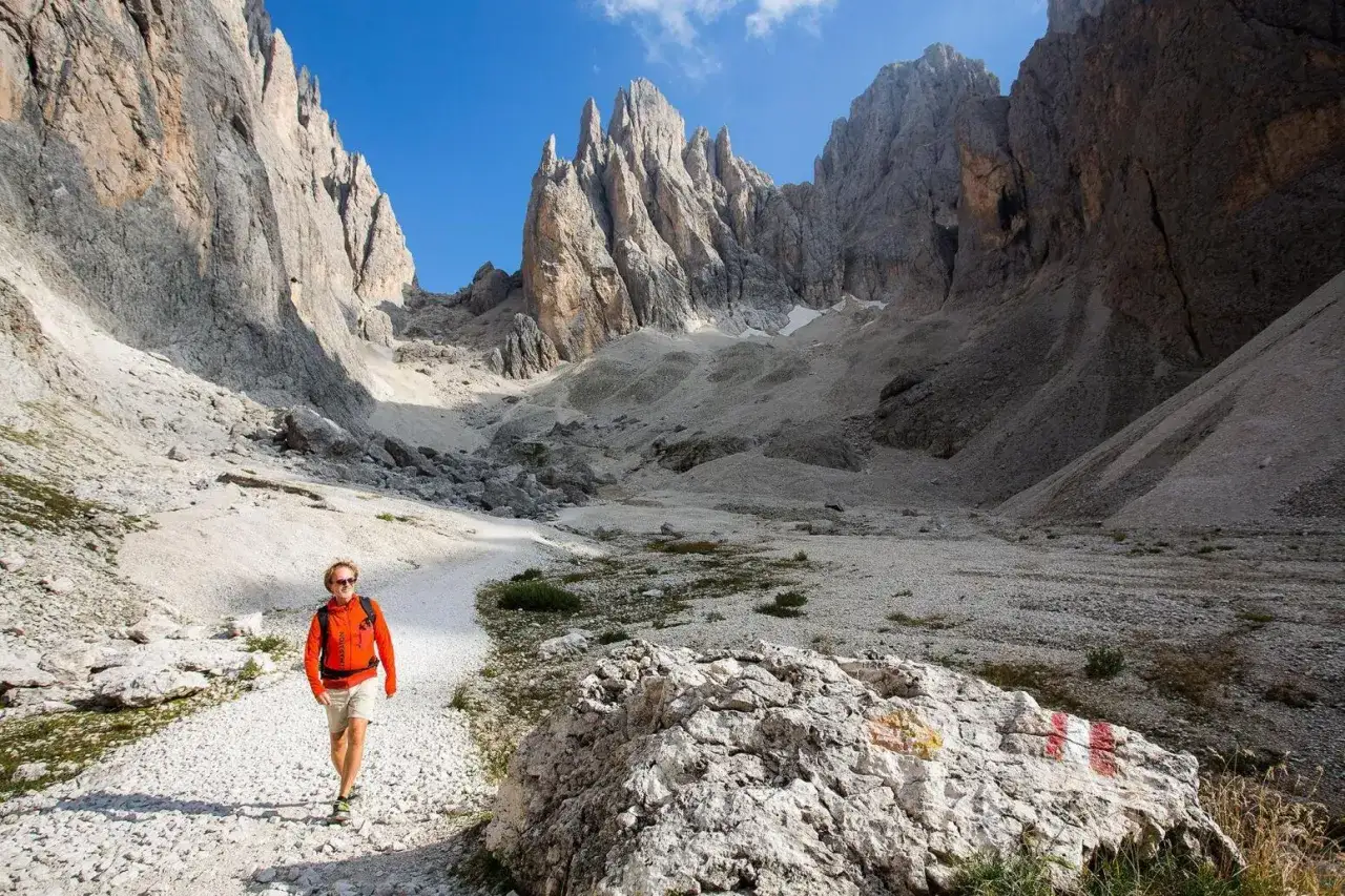 Vandrare njuter av en solig dag i Dolomiterna sommar, omgiven av dramatiska bergstoppar och grusiga stigar.
