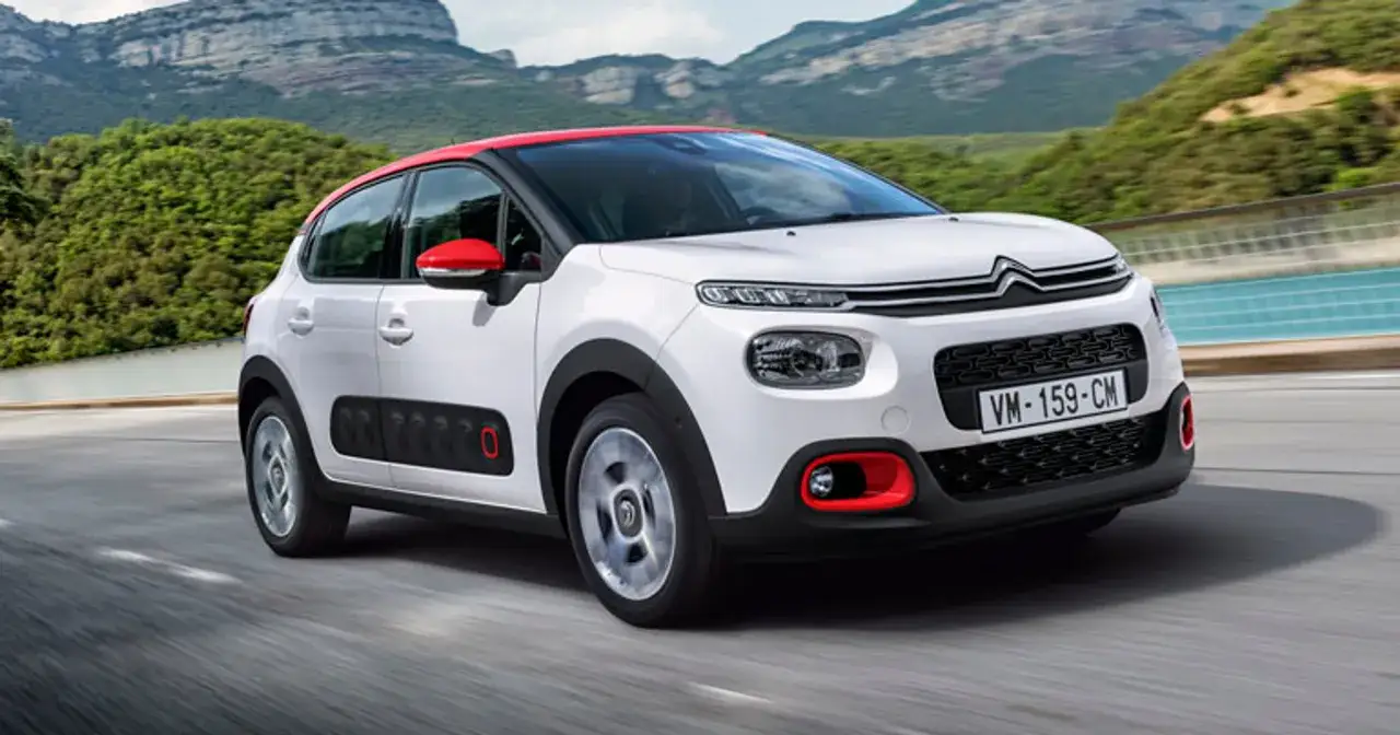 Biały Citroen C3 Cactus z czerwonym dachem i lusterkami pędzi po górskiej drodze.
