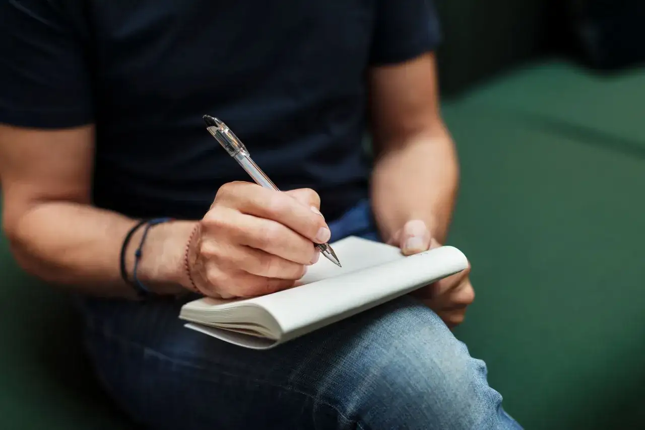 Man escribiendo en un cuaderno, buscando ejemplos de cómo contar la historia de mi vida.