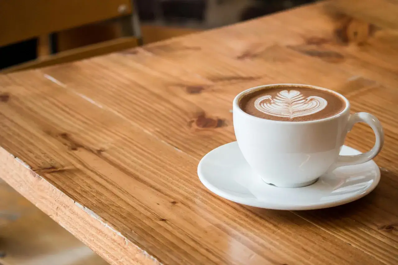 Idealna kawa flat white z pianką w kształcie serca na drewnianym blacie.