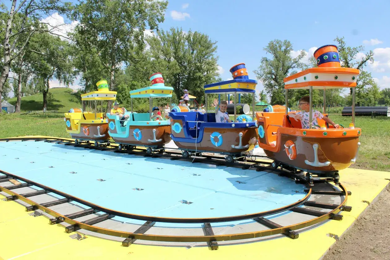 Kolejka w kształcie ł&oacute;deczek z dziećmi na pokładzie, wesoło mija się na torach w stężyca park rozrywki.