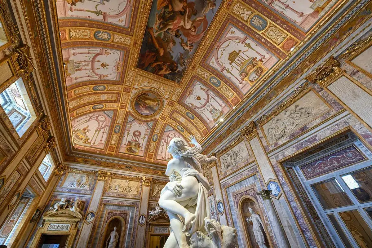 Magnifique sculpture au centre d'une salle ornée de fresques dorées. La **sculpture Villa Borghese** semble figée dans un mouvement dramatique, contrastant avec la richesse du décor.