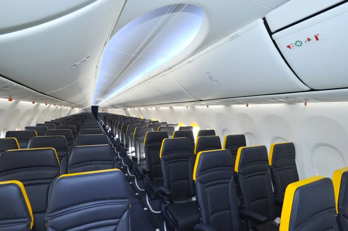 Puste rzędy czarnych siedzeń z żółtymi zagłówkami w samolocie. Trudno określić, ile jest miejsc w samolocie Ryanair, ale wygląda na to, że jest ich wiele.