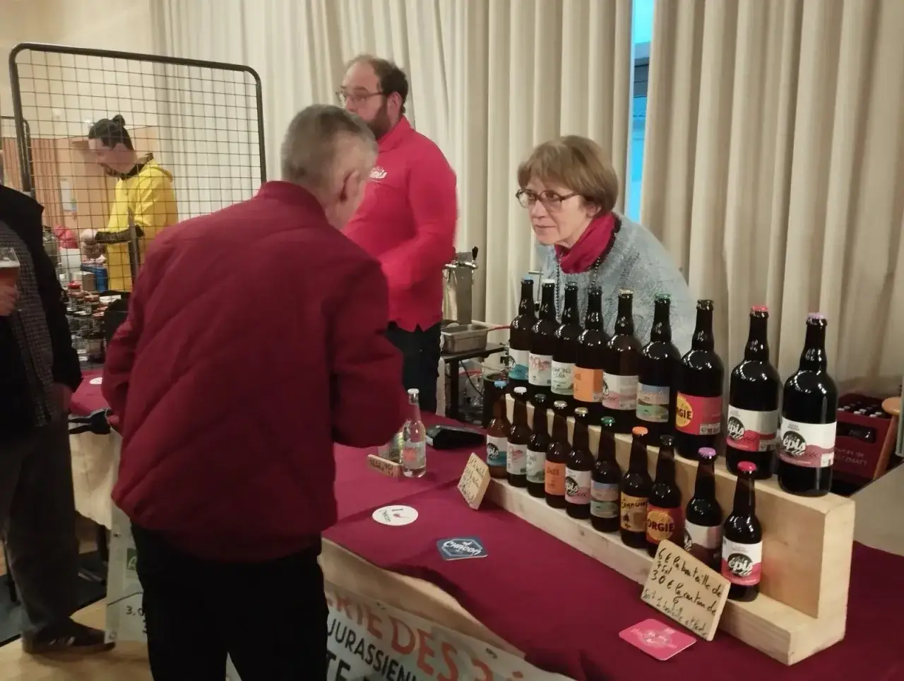 Des bouteilles de bi&egrave;re sont pr&eacute;sent&eacute;es lors d'une f&ecirc;te de la bi&egrave;re. Un homme discute avec une vendeuse.