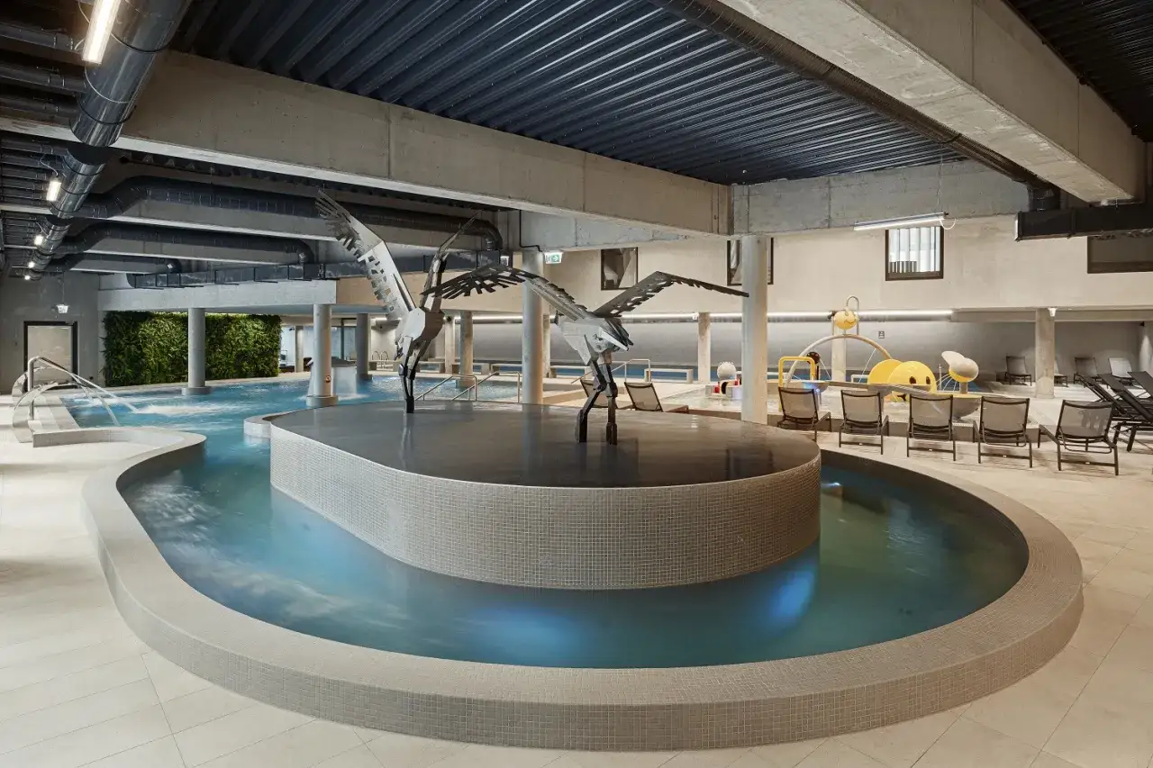 Wnętrze basenu w hotelu Lake Hill Mazury Resort & Spa z rzeźbami żurawi i zieloną ścianą.