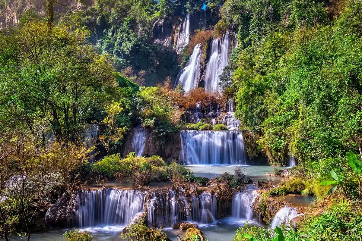 Majestätische Wasserfälle stürzen durch üppige Vegetation in einem **thailändischen Nationalpark**. Ein wahres Naturwunder!