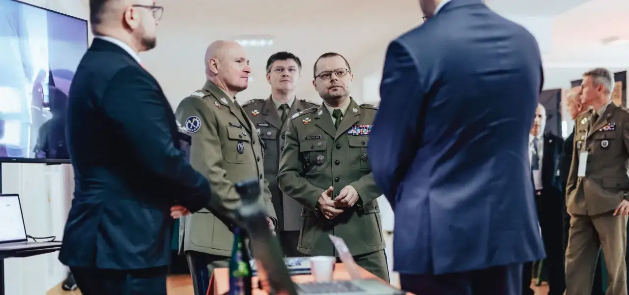 Wojsko prezentuje oferty pracy dla cywili. Mundurowi rozmawiają z mężczyznami w garniturach.