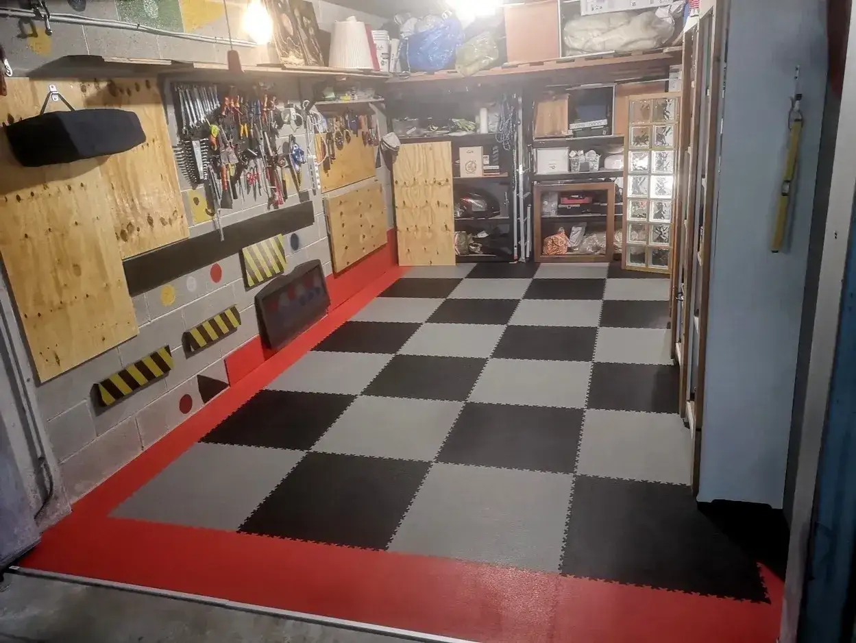 Pavimento a scacchi in piastrelle carrabili per garage, con bordi rossi e pareti attrezzate.