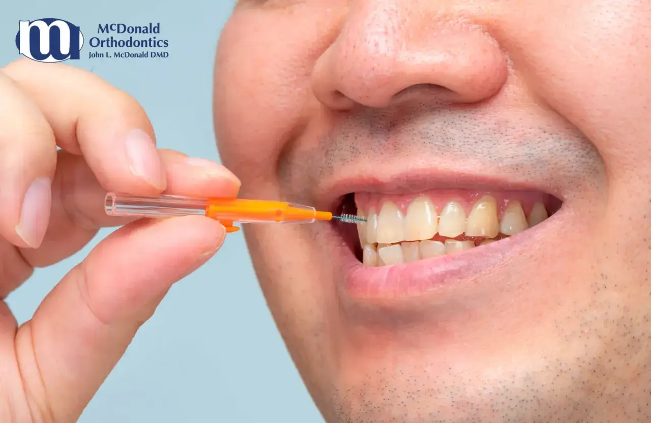Uomo usa scovolino denti per pulire tra i denti, mostrando come si usa per un sorriso sano.