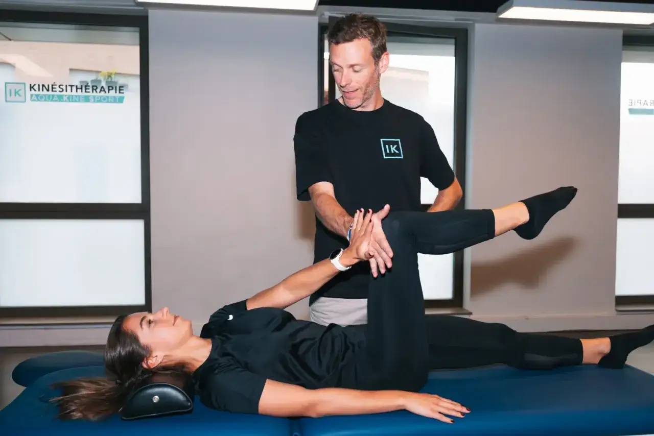 Un kin&eacute;sith&eacute;rapeute guide une patiente dans des exercices pour soulager la cruralgie. Elle est allong&eacute;e sur une table de massage, une jambe pli&eacute;e, l'autre tendue.