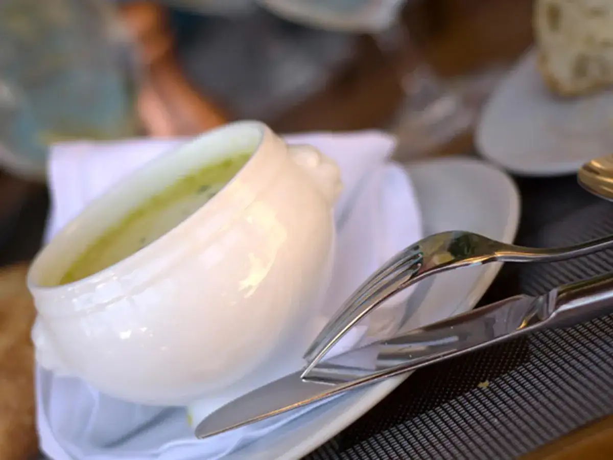 Eine cremige Spargelsuppe, zubereitet aus Spargelschalen, serviert in einer weißen Schüssel mit Besteck.
