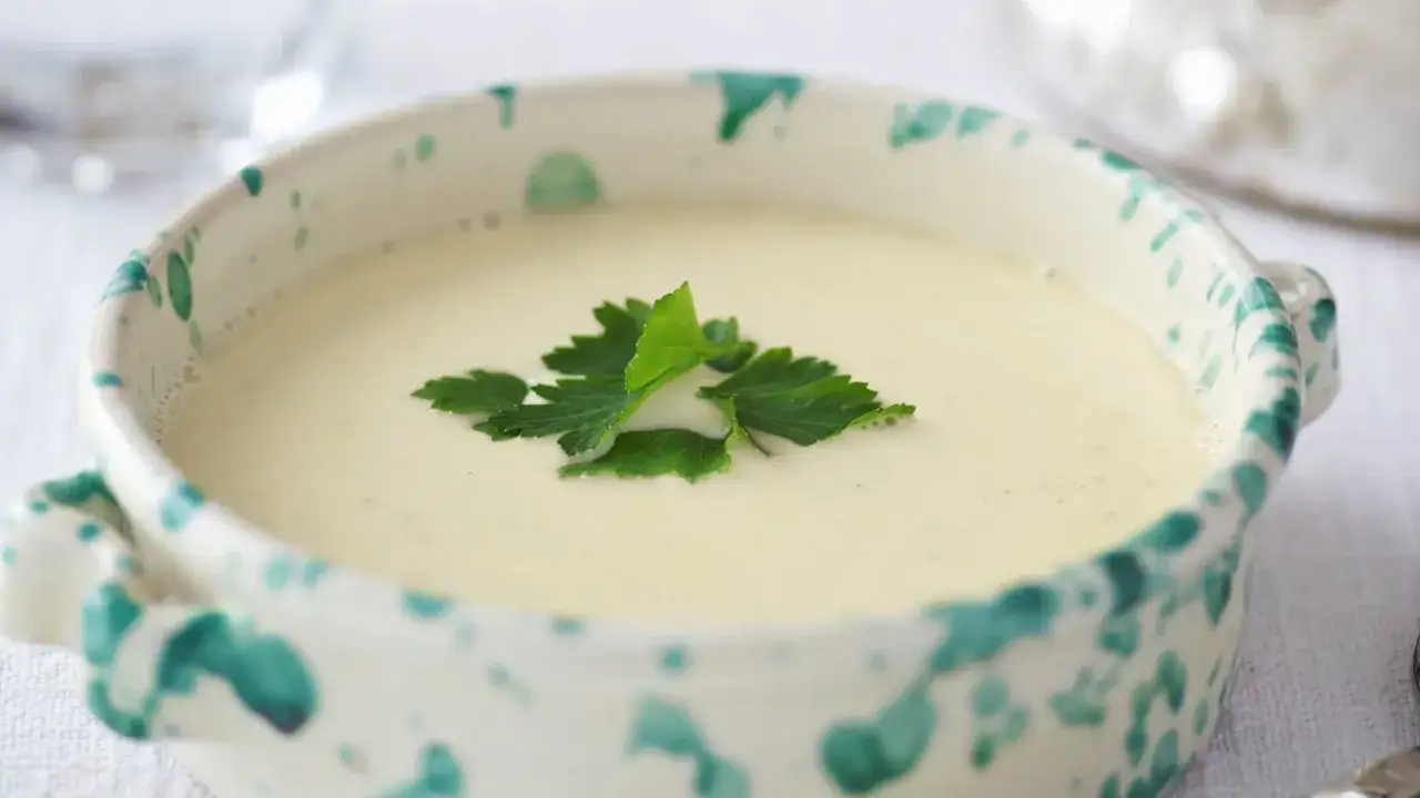 Una ciotola di crema di parmigiano, liscia e vellutata, guarnita con prezzemolo fresco.