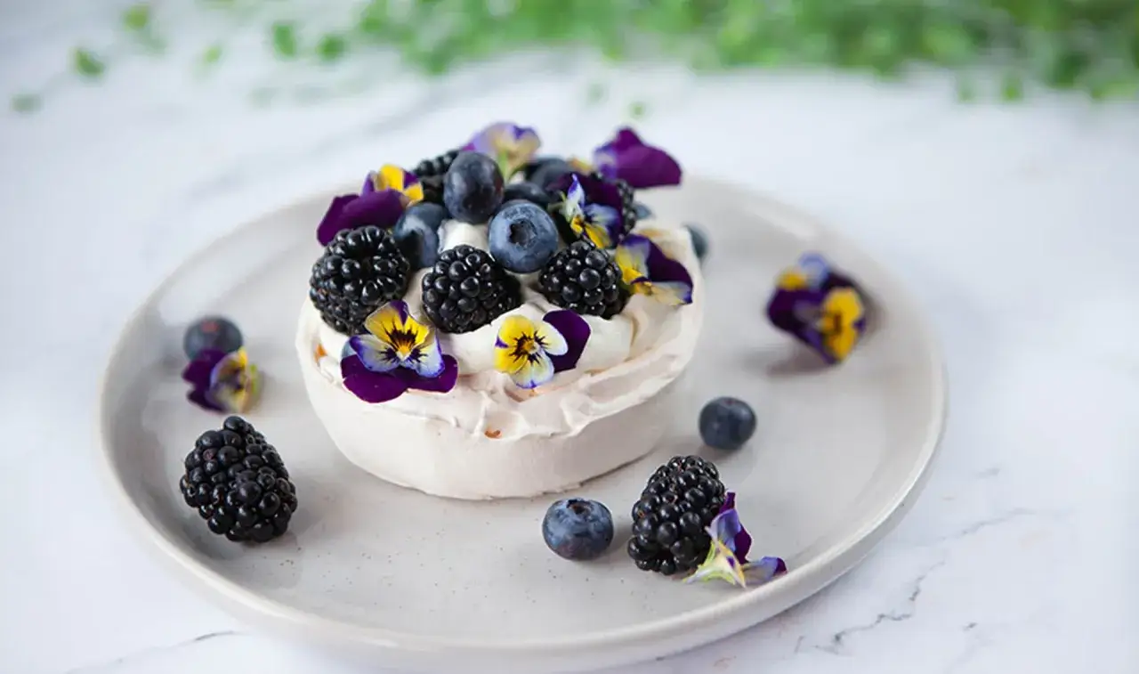 En liten pavlova toppad med färska bär och violer. En perfekt liten dessert för alla tillfällen.
