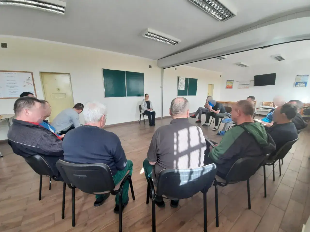 Grupa mężczyzn uczestniczy w sesji terapeutycznej, kt&oacute;ra jest częścią systemu terapeutycznego odbywania kary.