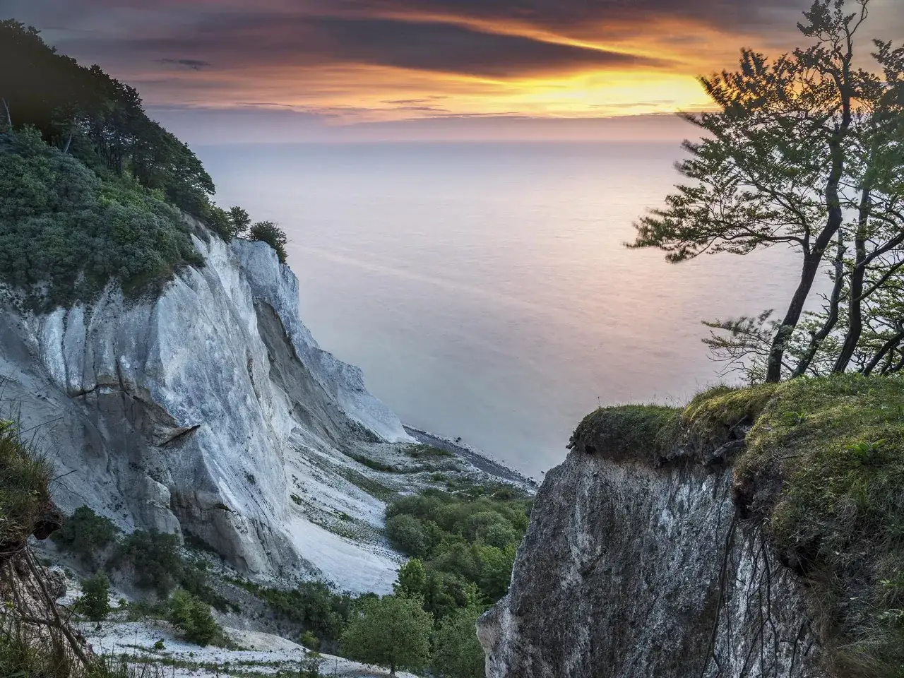 Vandra i Danmark vid de dramatiska vita klipporna vid havet under en f&auml;rgsprakande solnedg&aring;ng. En magisk vy.