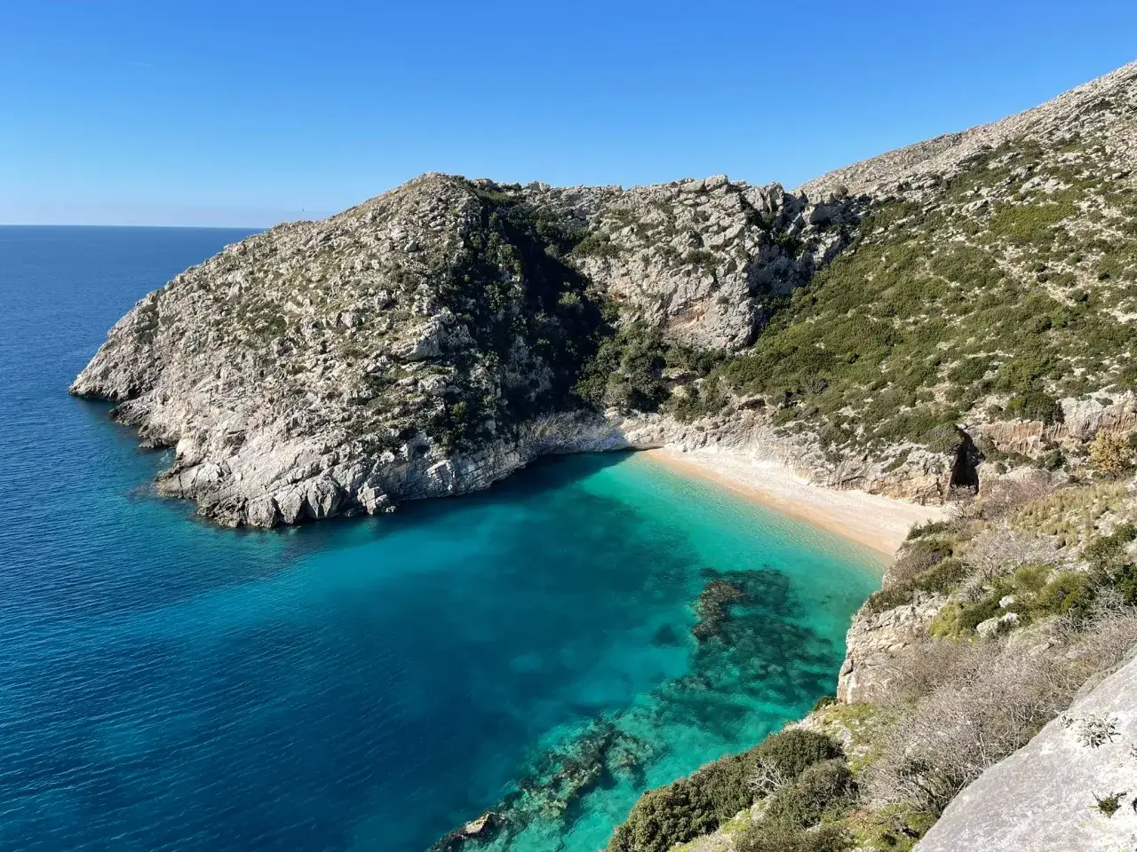 En avskild albanien strand med turkost vatten och klippiga berg. En dold p&auml;rla vid Medelhavet.