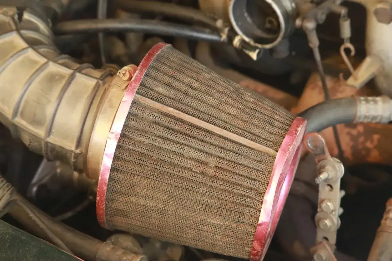Gros plan sur un filtre &agrave; air encrass&eacute;, montrant la poussi&egrave;re accumul&eacute;e qui &eacute;touffe le moteur.