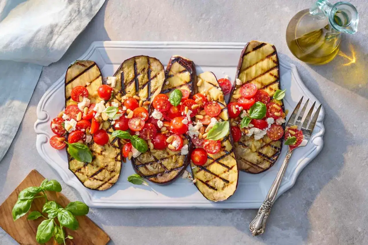 Grillad aubergine i ugn toppad med k&ouml;rsb&auml;rstomater, fetaost, pinjen&ouml;tter och basilika. En l&auml;cker och fr&auml;sch r&auml;tt.