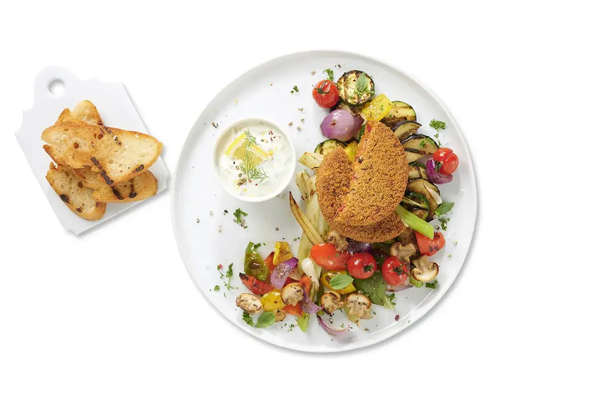 Assiette de l&eacute;gumes grill&eacute;s et galettes pan&eacute;es, servie avec une sauce blanche et des toasts. Un d&eacute;lice de saveurs, parfait avec de l'ail confit au four.