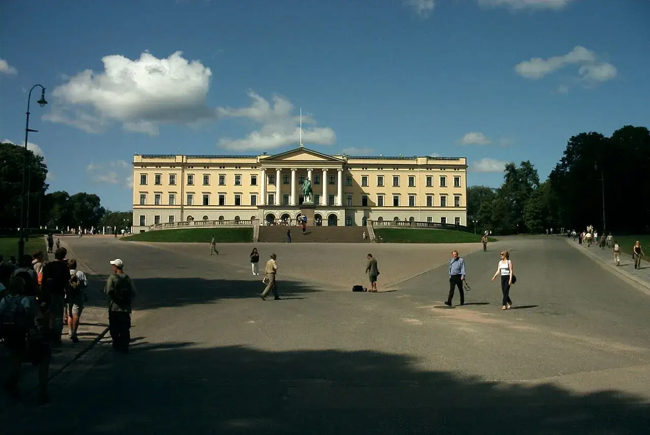 Det gula **Oslo slott** med sin imponerande fasad och staty framf&ouml;r. M&auml;nniskor promenerar p&aring; den stora, solbelysta ytan.