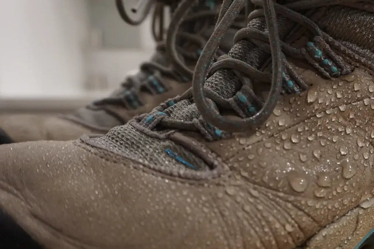 Close-up of a wet walking boot, showing water droplets on the tan material. This image might inspire a guide on how to clean walking boots after a muddy hike.