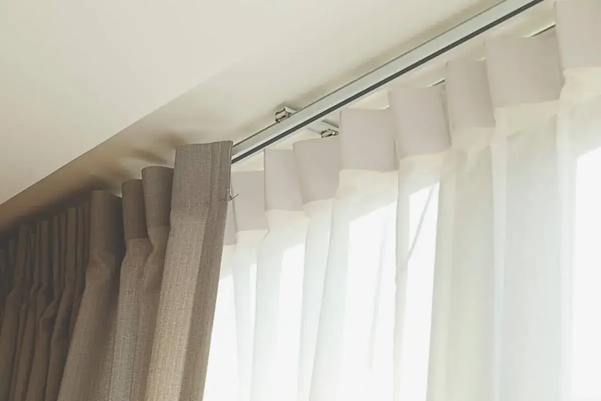 Detalle de rieles para cortinas, mostrando diferentes tipos de tela y su sistema de sujeci&oacute;n al techo.